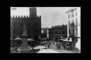 Cremona. Piazza Cavuor in un giorno di mercato. In primo piano il monumento di Vittorio Emanuele, sullo sfondo un lato del palazzo Comunale.