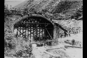 Ponte ferroviario con, in posa, gli operai addetti alla costruzione e le donne addette al trasporto dei materiali.