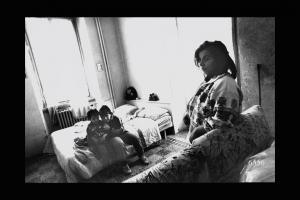 Giovane mamma con figli nella sua casa nel quartiere Molise. Milano. Madre con figli nella camera da letto della loro abitazione.
