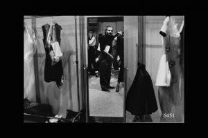 Lo stilista Gianni Versace riflesso nello specchio dei camerini di prova.
