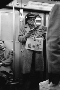 Uomo legge il quotidiano in metropolitana.