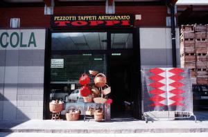 Negozio tappeti pezzotti con insegna "Pezzotti Tappeti Artigianato - Toppi". I pezzotti di Arigna. (Luoghi della tradizione del lavoro).