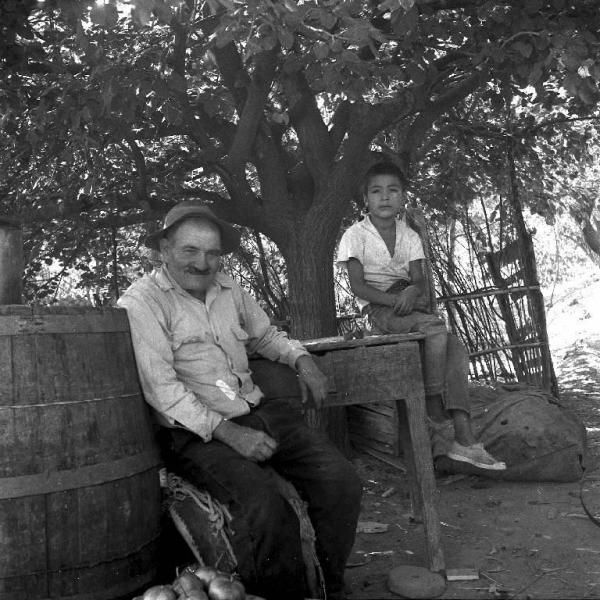 Melissa (Crotone) - Anziano contadino e bambino seduti nell'area esterna di una casa