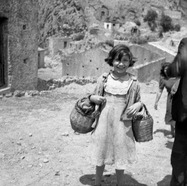 Melissa (Crotone) - Bambina con ceste al braccio in una strada
