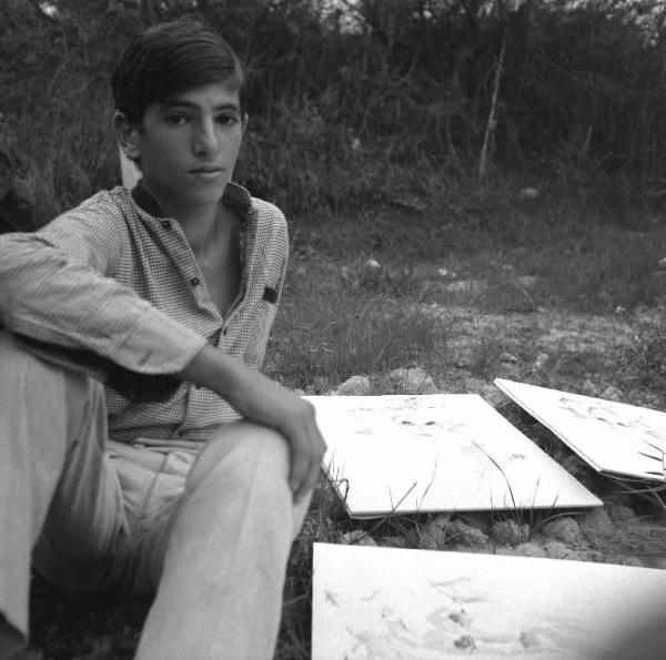 Melissa (Crotone) - Ragazzo seduto in un campo con disegni di Ernesto Treccani - Ritratto