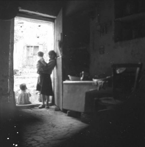 Melissa (Crotone) - Bambina con bambino più piccolo in braccio e altri bambini sull'uscio di una casa