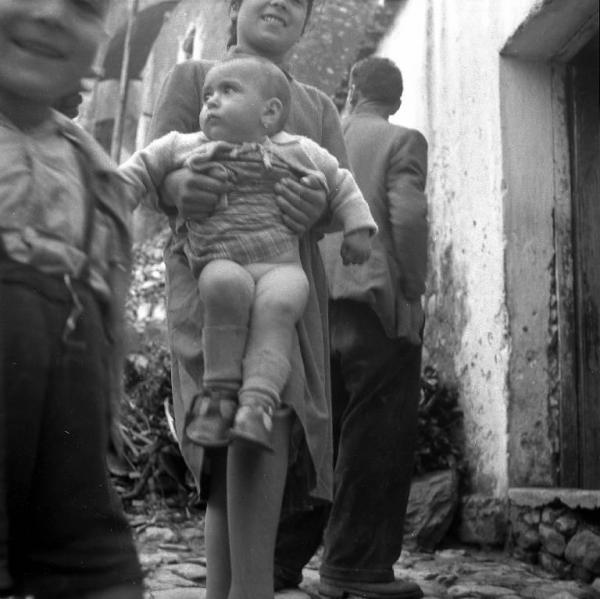 Melissa (Crotone) - Bambina con bambino più piccolo in braccio all'esterno di una casa