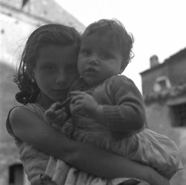 Melissa (Crotone) - Bambina con bambina più piccola in braccio in una strada - Ritratto