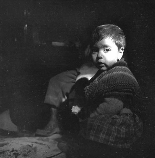 Melissa (Crotone) - Bambino piccolo seduto vicino al braciere in un interno di casa