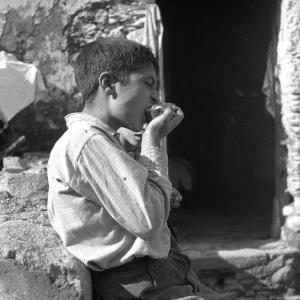 Melissa (Crotone) - Bambino che mangia un panino sull'uscio di una casa