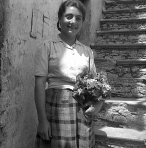 Melissa (Crotone) - Giovane donna con mazzolino di fiori all'esterno di una casa - Ritratto