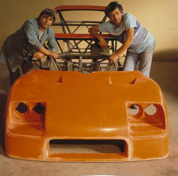 Autofficina macchine sportive - due maestranze posano di fianco a una vettura