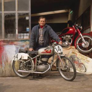 Moto officina - il titolare posa accanto a una moto d'epoca davanti all'ingresso
