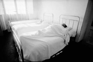 Stanza da letto di un ospedale psichiatrico con paziente sotto le coperte