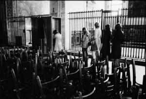 Sedie accatastate in una chiesa - Sullo sfondo persone in fila per il confessionale