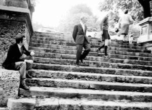 Ritratto di giovane seduto e ragazza che scende le scale in un parco