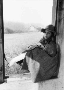 Carola seduta nel vano vuoto di una finestra abbandonata