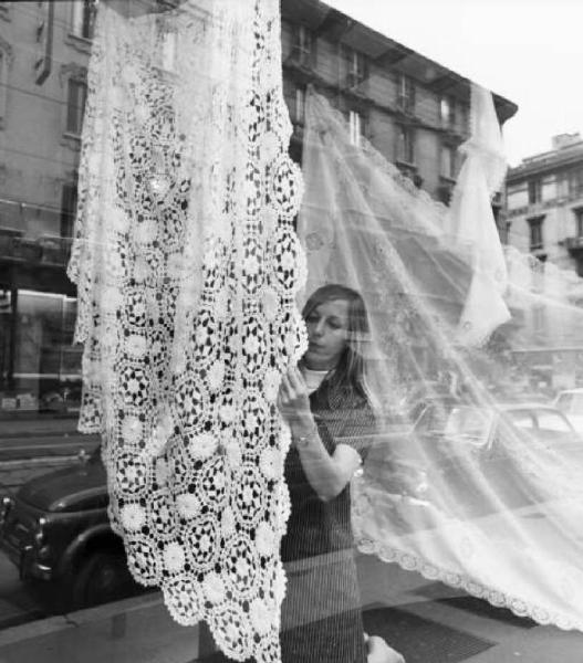Giovane donna con tovaglia ricamata in una vetrina di negozio