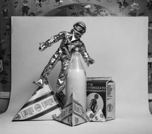 Still - life con bottiglia di latte, cartoni da un litro, tetrapack e modellino di astronauta