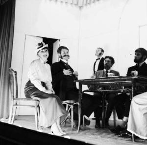 Nizza - rappresentazione teatrale - Attori e attrici in costume sul palcoscenico attorno ad un tavolo - sullo sfondo il maggiordomo
