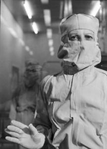 Glaxo - Ritratto di un ricercatore in camice bianco, guanti e mascherina in un laboratorio - sullo sfondo un altro medico