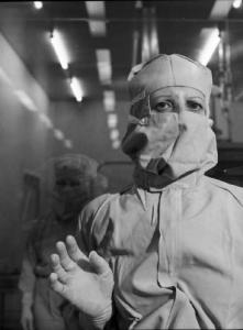 Glaxo - Ritratto di un ricercatore in camice bianco, guanti e mascherina in un laboratorio - sullo sfondo un altro medico