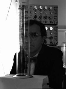 Glaxo - Ritratto di un ricercatore dietro una provetta graduata - alle sue spalle apparecchiature da laboratorio