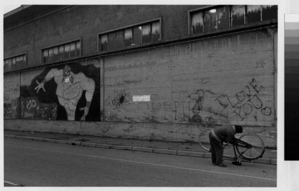 Rho - via Enrico Mattei - muro di cinta con murales - uomo che ripara la bicicletta