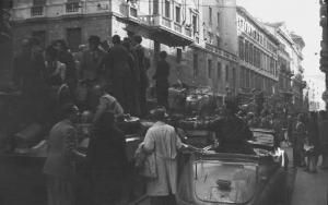 Seconda Guerra Mondiale. Liberazione di Milano. 29 Aprile 1945. Corso Monforte nei pressi del Palazzo del Governo sede della Prefettura, colonna di carri armati Sherman dell'esercito americano sommersi dalla folla in festa.