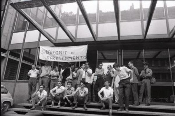 Sciopero dei dipendenti della Sidercomit: i lavoratori si sono seduti di fronte all'ingresso dell'edificio della Direzione dell'azienda e mostrano uno striscione con la scritta "Sidercomit = sfruttamento"