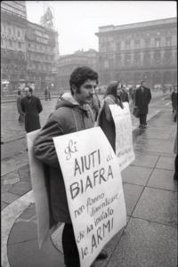 Manifestazione per il Biafra: un manifestante, in primo piano, porta un cartello con la scritta "gli AIUTI al BIAFRA non fanno dimenticare chi ha inviato le ARMI"
