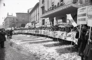 Sciopero dei Tessili di Monza: i lavoratori, di fronte al cinema Centrale di Monza, mostrano un lungo striscione con scritte e disegni. Molti di loro hanno dei fischietti e portano dei cartelli