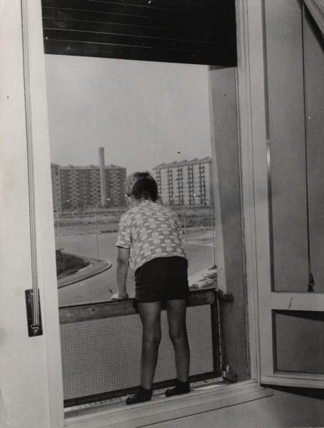 Milano - Quartiere Gallaratese - Interno di appartamento - Bambino si sporge da un basso balcone - Sullo sfondo palazzi di edilizia popolare