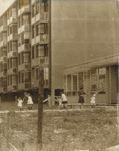 Milano - Quartiere Chiesa Rossa - Bambini giocano all'esterno della scuola materna - Palazzi sullo sfondo - Edificio prefabbricato - Terreno incolto