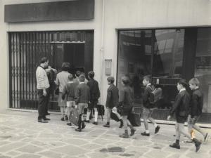 Milano - Quartiere Gratosoglio -  Scuola elementare sistemata in un negozio - Ingresso di bambini di una classe maschile con la maestra - Commessi scolastici
