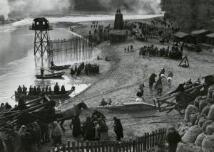 Scena del film "Fabiola" - Regia Alessandro Blasetti, 1949 - Su una spiaggia si radunano in gruppi attori non identificati in vesti da soldati, che sbarcano dal mare. Sullo sfondo del fumo e delle torrette con recinti in legno.
