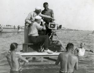 Sul set del film "La famiglia Brambilla in vacanza" - Regia Carl Boese, 1941 - Il regista Carl Boese e due operatori non identificati su una zattera indicano l'acqua intenti a girare una scena del film. Intorno a loro, attori non identificati.