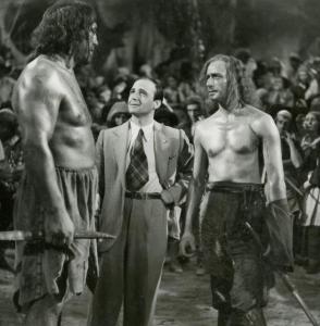 Sul set del film "La figlia del corsaro verde" - Guazzoni, Enrico, 1940 - Primo Carnera, a sinistra con un arma in mano, osserva, ricambiato, un'operatore non identificato, al centro e Fosco Giachetti, a destra.