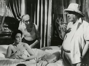 Scena del film "La figlia di Mata Hari" - Merusi, Renzo, 1954 - Un attore non identificato, a destra, e Ludmilla Tcherina, stesa su un letto coperta da un lenzuolo, si osservano. Dietro, Valéry Inkijinoff le si avvicina e sorridente.