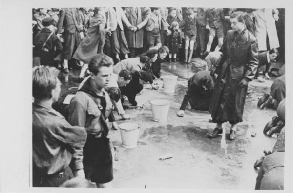 Nazismo - Austria, Vienna - Lavori forzati - Uomini e donne ebree puliscono in ginocchio una strada costretti dalla gioventù hitleriana (Hitlerjugend) - Folla osserva - Antisemitismo
