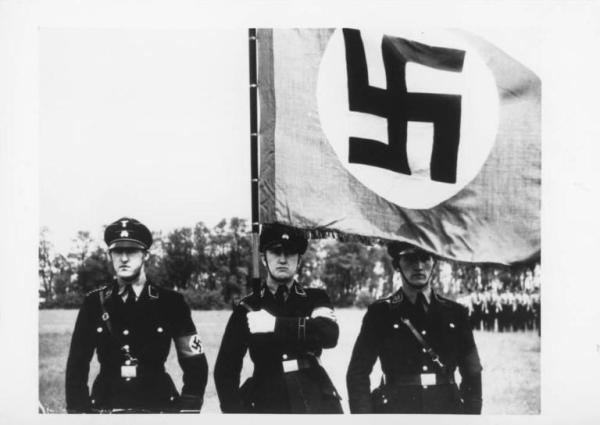 Germania, Monaco - Parata militare nazista - Ritratto di gruppo: 3 SS in divisa con bandiera nazista (svastica / croce uncinata)