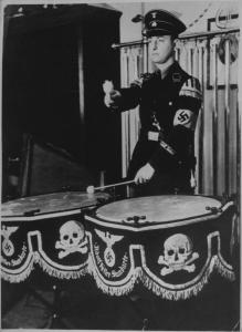 Germania - Esecuzione dell'inno delle SS - Ritratto maschile: giovane militare in divisa suona i tamburi - Svastica (croce uncinata) - Drappi con teschio e aquila con svastica - Nazismo
