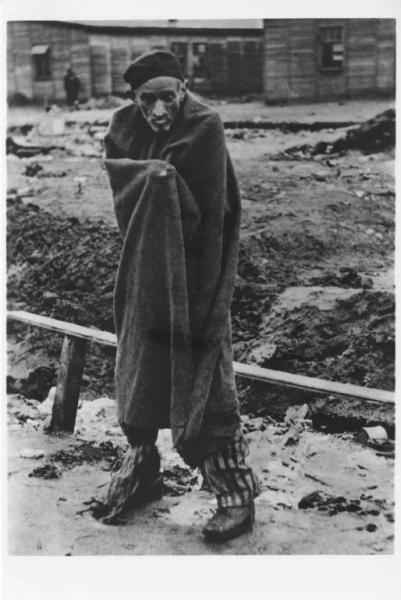Seconda guerra mondiale - Germania - Campo di concentramento di Sandbostel per prigionieri di guerra - Nazismo - Liberazione - Ritratto maschile: prigioniero politico, ebreo ungherese, scheletrito sopravvissuto, avvolto in una coperta - Baracche