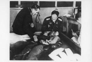 Seconda guerra mondiale - Nazismo - Germania - Campo di concentramento di Dachau - Laboratorio, interno - Esperimenti sul congelamento - Vasca con acqua gelata - Prigioniero immerso - Ufficiali SS in divisa / Le SS sono Ernst Holzlöhner (a sx), Sigmund Rascher (a dx)