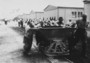 Seconda guerra mondiale - Nazismo - Germania - Campo di concentramento di Dachau - Cortile interno - Lavori forzati - Kommando di prigionieri spingono vagonetto - Baracche