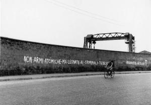Scritte murali. Sesto San Giovanni - Paesaggio industriale - Fabbrica - Muro di cinta - Scritta murale - Carroponte - Uomo in bicicletta